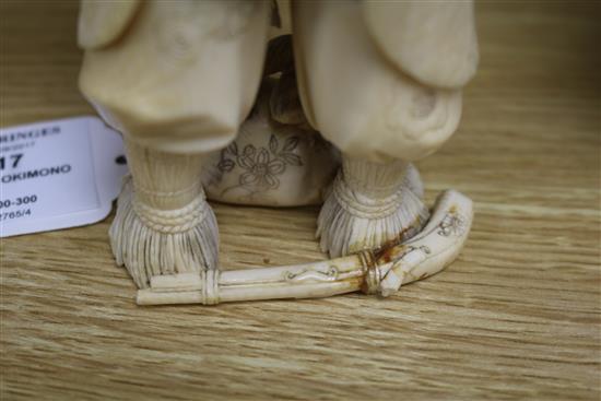 A Japanese carved ivory okimono of a huntsman, Meiji period, holding a hawk and a brace of birds